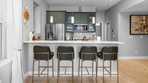 Una cocina moderna con taburetes de bar, refrigerador, microondas y un amplio ventanal.