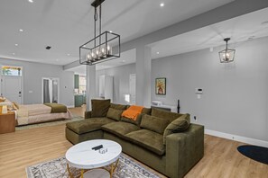 Una sala de estar moderna con un sofá modular, una mesa de centro redonda e iluminación colgante.