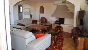 Un salón con sofá, sillón, mesa de centro, chimenea y televisión.