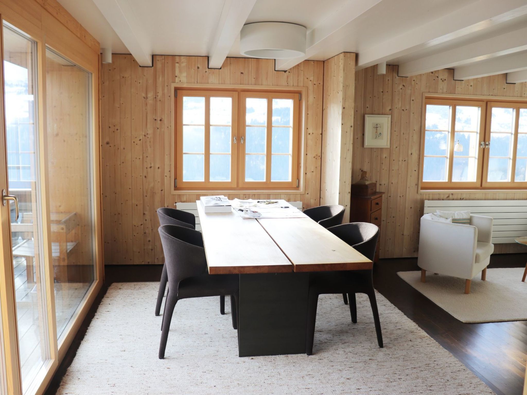 A dining area with a long wooden table, black chairs, and a white sofa.