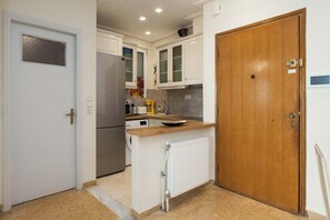 A compact kitchen with white cabinets, a wooden countertop, a built-in oven, and a white radiator. - Lovely 1 Bd Apt with Balcony 10 min from Acropolis (Athina)