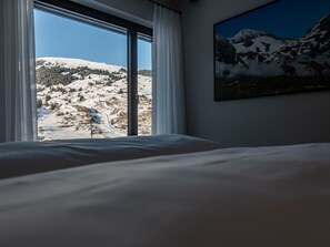 A hotel room with a large window offering a view of a snowy mountain landscape. - Tschuppina Schiess, Brigels, (Breil/Brigels), 65092B by Interhome (Breil/Brigels)