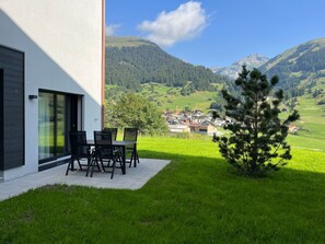 A modern building with a patio area, a table with chairs, and a view of a mountainous landscape. - Tschuppina Schiess, Brigels, (Breil/Brigels), 65092B by Interhome (Breil/Brigels)