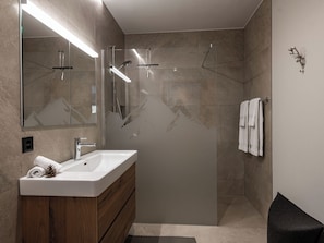A modern bathroom with a glass-enclosed shower, a wooden vanity, and a large mirror.