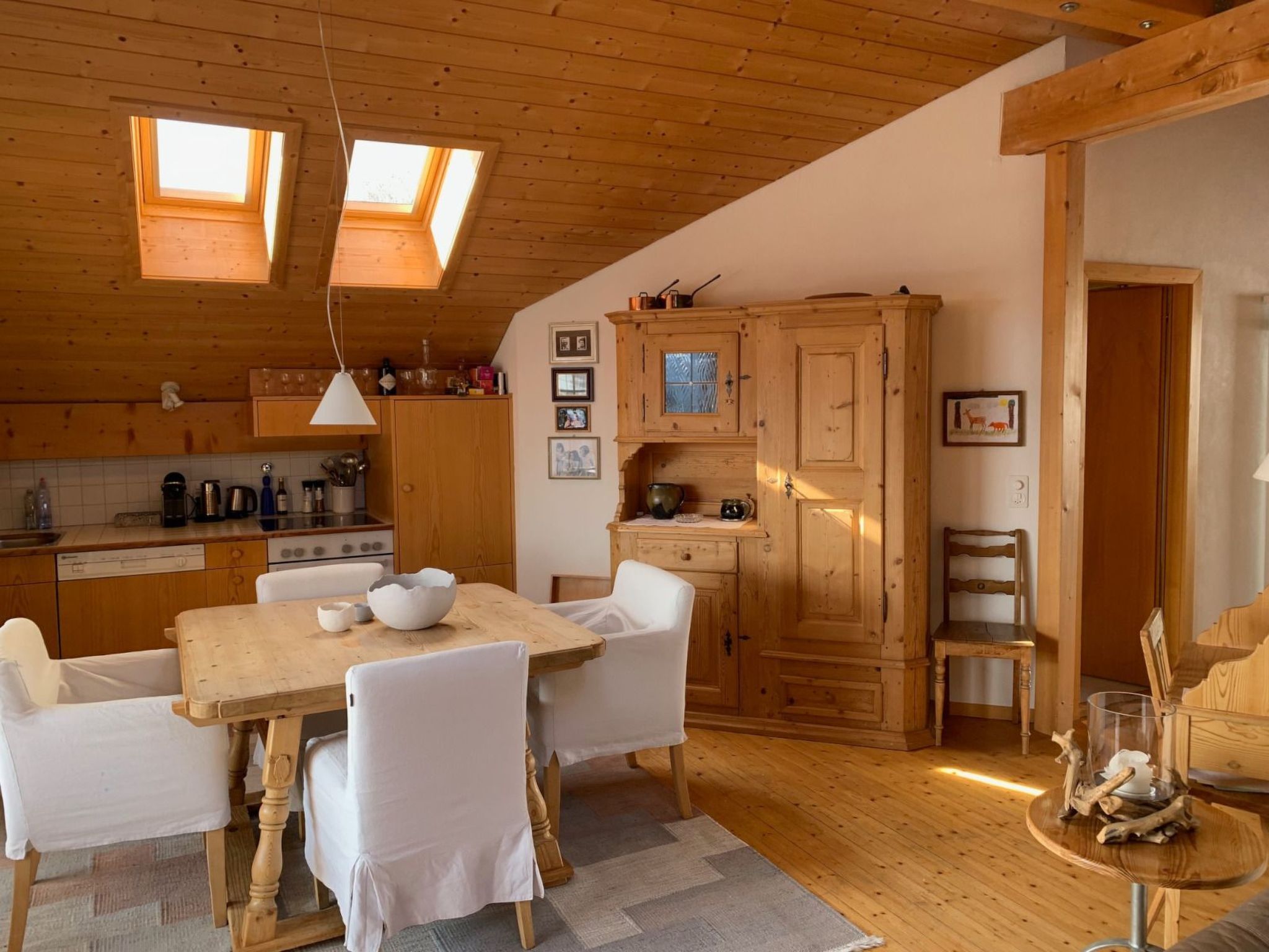 A cozy kitchen with wooden cabinets, a dining table, and two skylights.