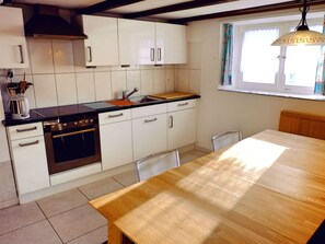 A kitchen with white cabinets, a wooden table, and a window with curtains.