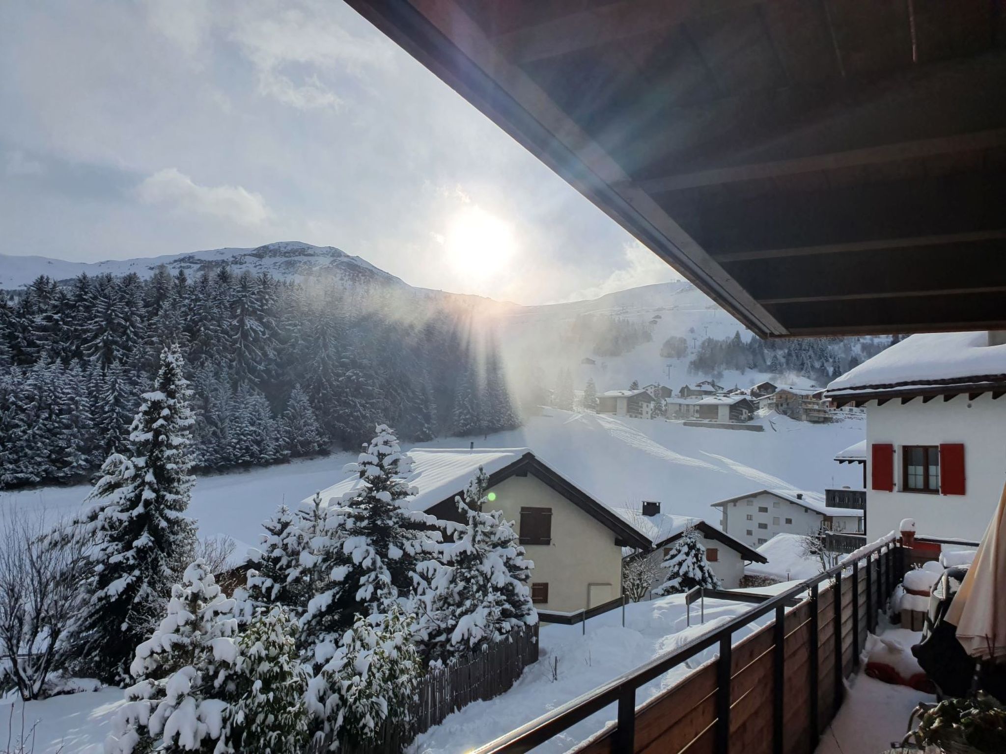 Paisaje nevado de montañas con vistas a una zona residencial y una casa con balcón.