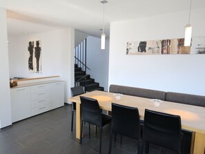 A modern kitchen with a dining area, featuring a wooden table, black chairs, and a staircase leading to an upper level. - Ferienhaus Davos Munts, Vattiz, (Vattiz), 46012B by Interhome (Vattiz)