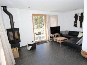 A modern living room with a black wood-burning stove, a flat-screen TV, a sofa, and a dining area. - Ferienhaus Davos Munts, Vattiz, (Vattiz), 46012B by Interhome (Vattiz)