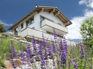 A two-story house with a balcony, surrounded by natural vegetation and rocks. - Ferienhaus Davos Munts, Vattiz, (Vattiz), 46012B by Interhome (Vattiz)