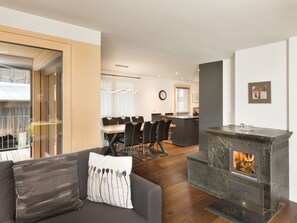 A modern living room with a fireplace, a dining area, and a kitchen. - Vitg Vattiz, Vattiz, (Vattiz), 46002B by Interhome (Vattiz)