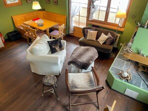 Un salon chaleureux avec une table à manger en bois, deux canapés, un petit tabouret et une cheminée.