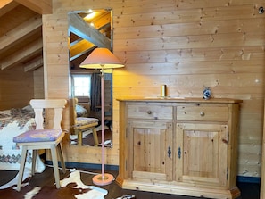 A wooden cabin room with a bed, a chair, a dresser, and a lamp. - Casa Belinda Haht, Brigels, (Breil/Brigels), 65062B by Interhome (Breil/Brigels)