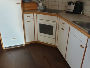 Cuina amb armaris blancs, forn integrat, rentapesos i cafetera.