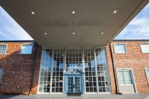 A building with large glass windows, a brick facade, and a blue entrance with a peaked roof. - Sleek- Mins To - Atrium Health & CIA & Stadium (Charlotte)