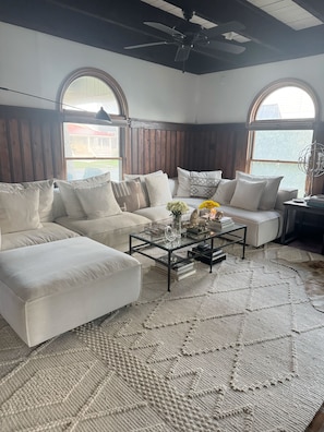 A living room with a sofa, armchairs, a coffee table, and a rug.