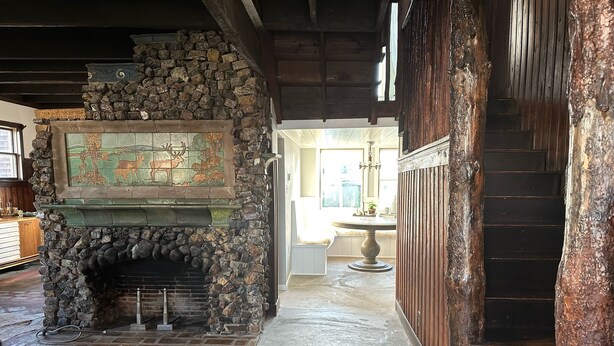 Una chimenea de piedra con un mosaico, un banco de madera y una escalera.