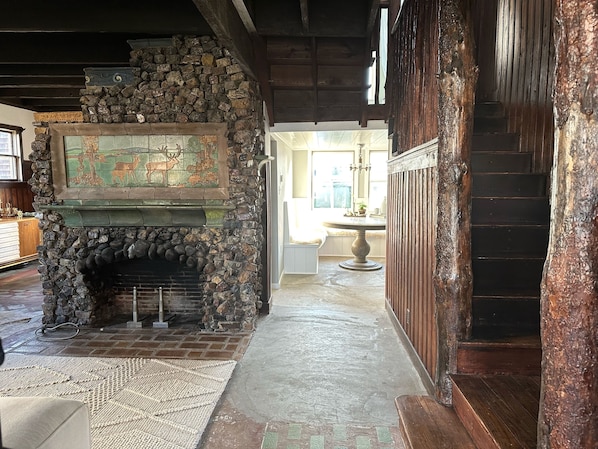 A stone fireplace with a mosaic, a wooden bench, and a staircase.