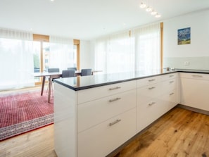 Eine moderne Küche mit weißen Schränken, einer schwarzen Arbeitsplatte und einem Holzboden.