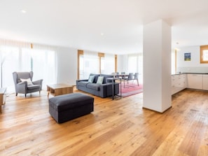 Ein geräumiger Wohnbereich mit einer Couch, Hocker und einem Esstisch.