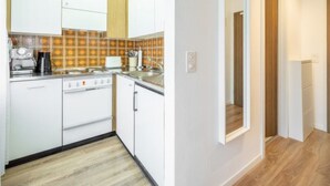 Eine kleine Küche mit weißen Schränken, einer Kaffeemaschine und einem Toaster.