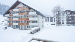 Ein mehrgeschossiges Gebäude mit Balkonen, eine verschneite Landschaft und ein klarer Himmel.