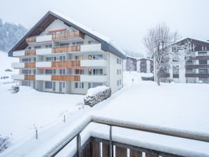 A multi-story building with balconies, a snow-covered landscape, and a clear sky. - Val Signina 2-9 by Interhome (Laax)