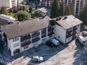 A multi-story building with balconies, a parking area, and a small garden. - Cristallina A2 by Interhome (Laax)