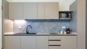 A modern kitchen with a built-in microwave, a sink with a faucet, and a countertop with a kettle and coffee maker. - Flower Residence - Appartamento Begonia (Lissone)