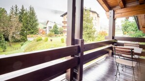 A wooden deck with a view of a green landscape and buildings. - Casa la Streila by Interhome (Laax)
