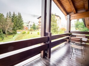 Een houten terras met uitzicht op een groen landschap en gebouwen.