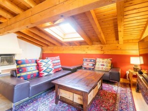 A cozy loft-style room with a wooden ceiling, a sofa set, a coffee table, and a patterned rug. - Casa la Streila by Interhome (Laax)