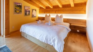 A bedroom with a wooden ceiling, a bed with white bedding, and two posters on the wall. - Casa la Streila by Interhome (Laax)