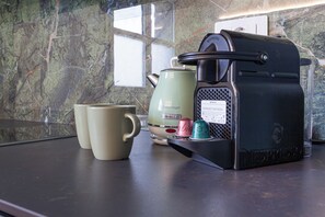 Eine Kaffeemaschine, zwei Tassen und ein Wasserkocher auf einer Arbeitsplatte.
