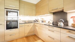 Eine moderne Küche mit Holzausstattung, einem Kombidämpfer und einer schwarzen Arbeitsplatte.