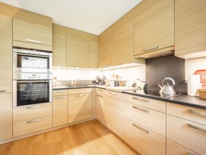 Una cocina moderna con armarios de madera, un horno doble y una encimera negra.