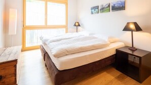 Ein Schlafzimmer mit einem Bett, zwei Nachttischlampen, einem Nachttisch, einem Fenster und drei Wandbildern.