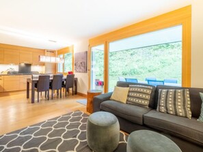 Un salon moderne comprenant un canapé, des poufs et un coin repas avec des chaises et une table.