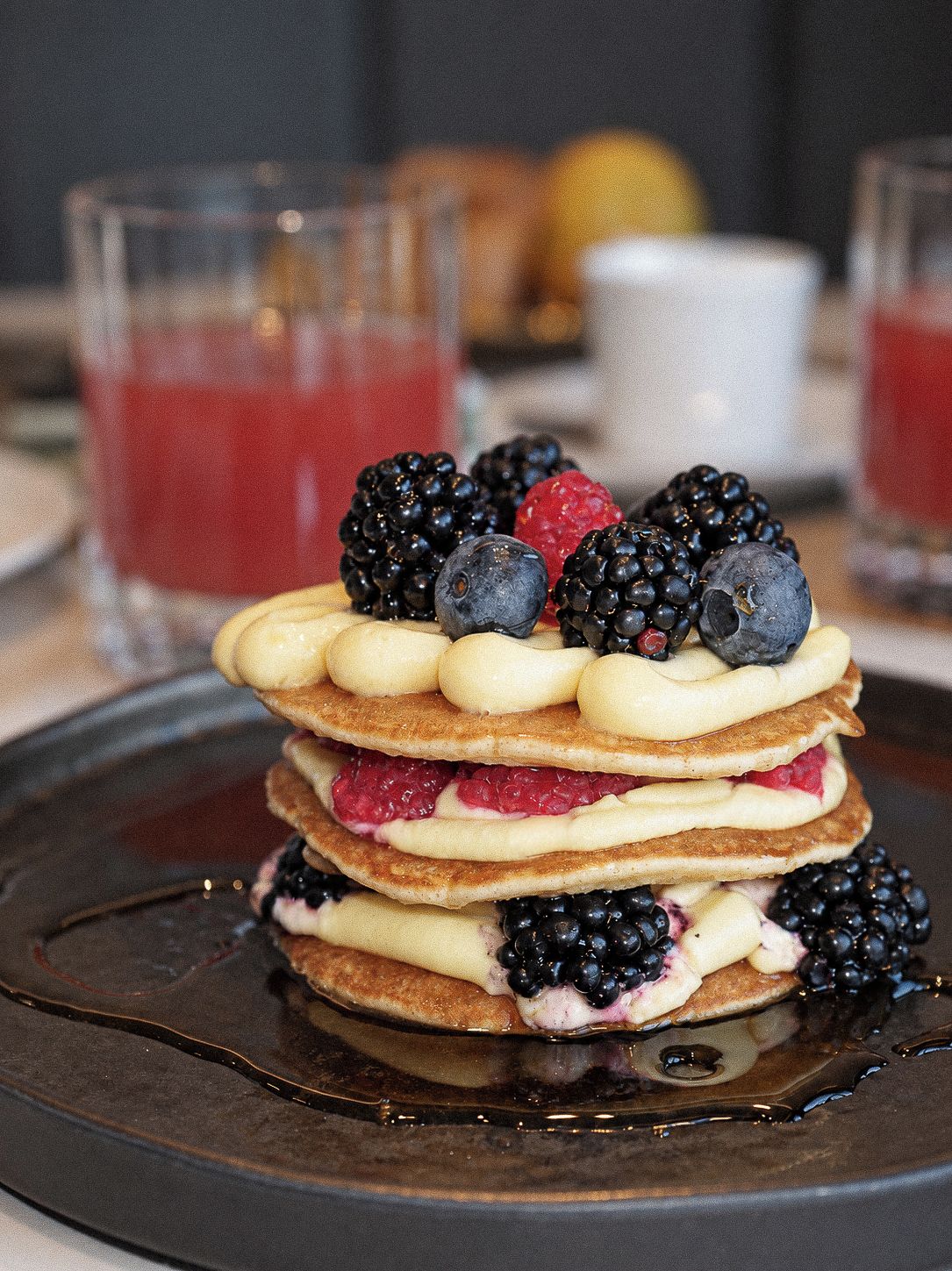 A stack of pancakes with berries and syrup on a plate.
