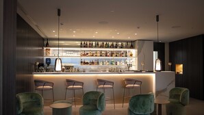 A bar area with a marble countertop, multiple bar stools, and a variety of bottles.