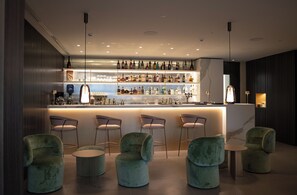 A bar area with a marble countertop, multiple bar stools, and a variety of bottles.