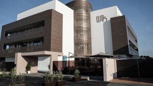 A modern building with a cylindrical central tower, a flat roof, and a large entrance with a covered area.