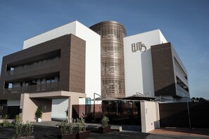 A modern building with a cylindrical central tower, a flat roof, and a large entrance with a covered area. - Elitis House Suite & Spa (Nova Milanese)