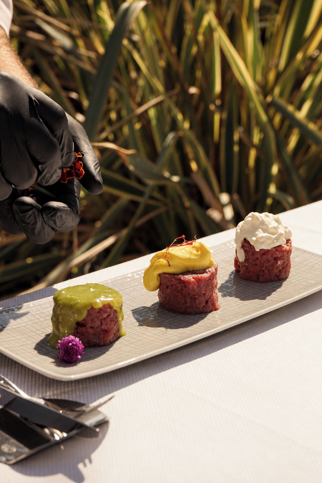 Un plato con tres alimentos, un cuchillo y un par de guantes.