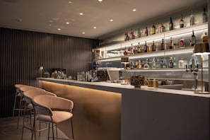 A bar area with a counter, stools, and shelves of bottles. - Elitis House Suite & Spa (Nova Milanese)
