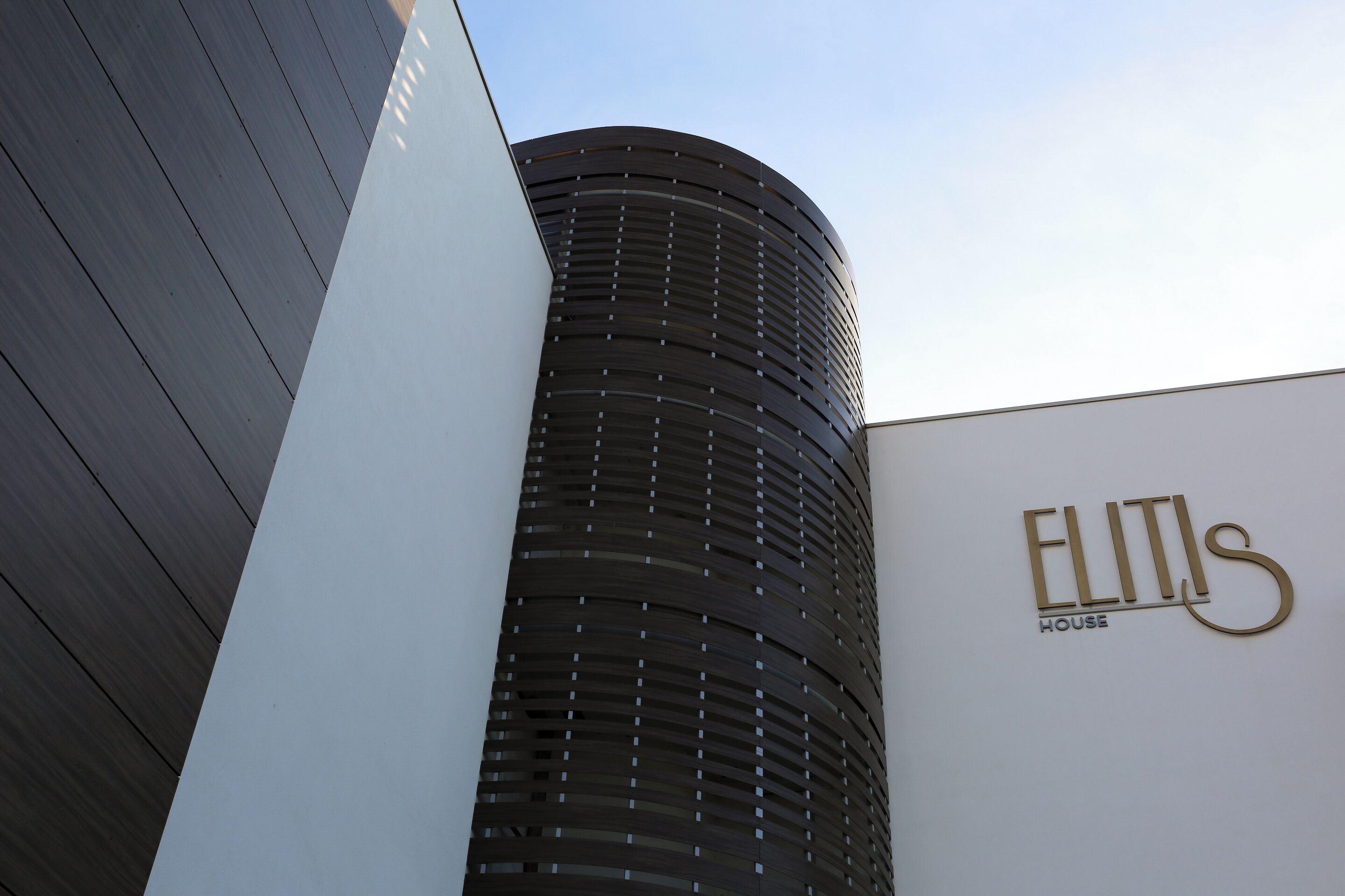 Un edificio moderno con fachada curva y un letrero que dice 'ELITIS HOUSE'.