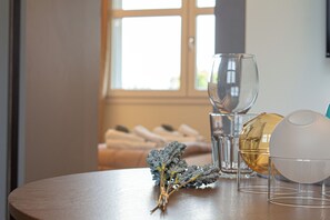 Ein Holztisch mit einem Glas, einer weißen, kugelförmigen Figur und einem Strauß getrockneter Blumen.