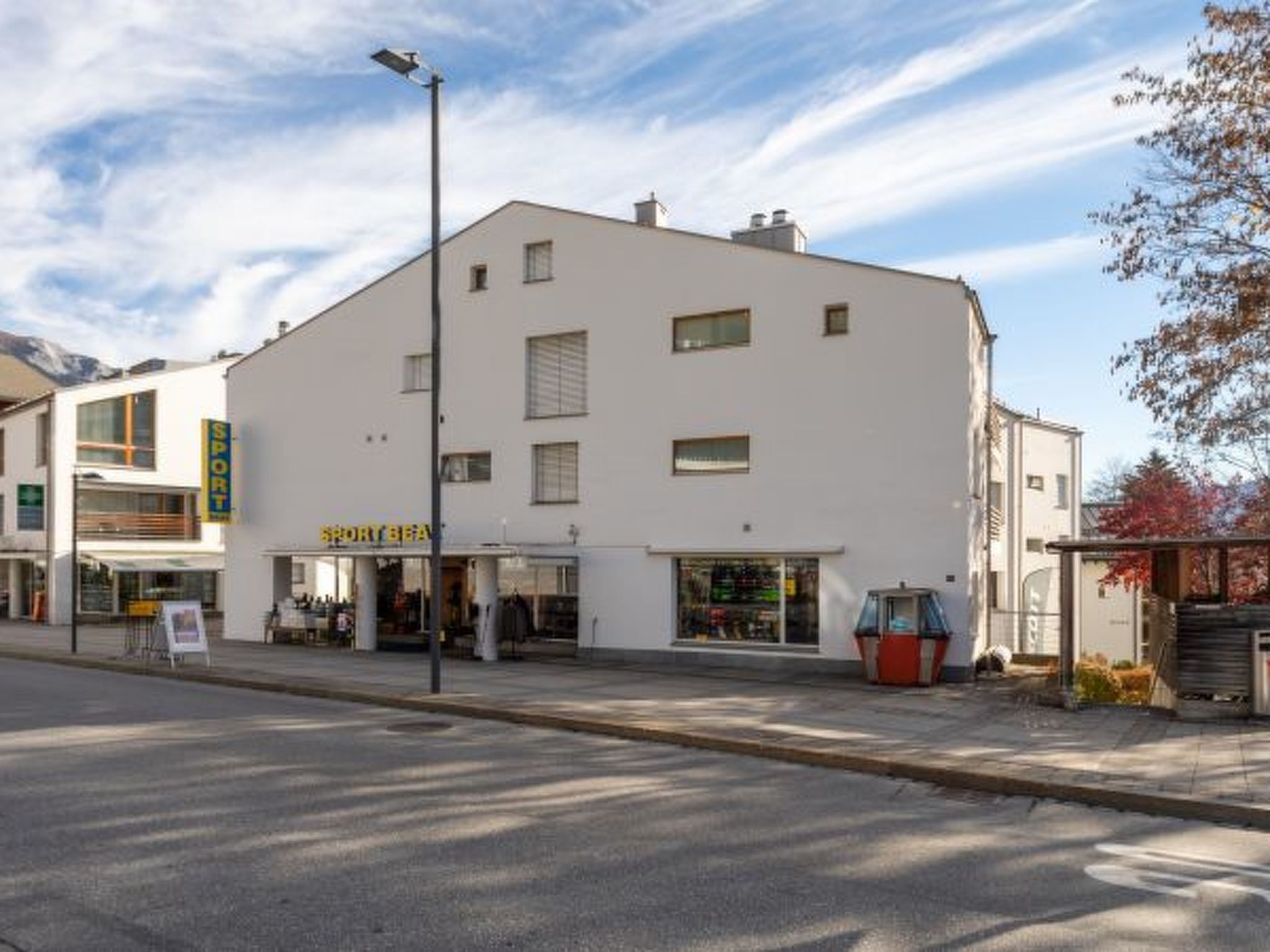 Ein weißes Gebäude mit einer Fassade, auf der 'SPORTBEA' steht, und eine Straßenlaterne.