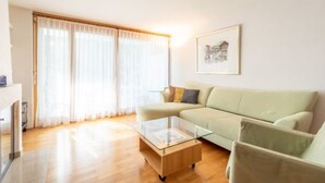 A living room with a sofa, a glass coffee table, and a fireplace. - Capolgarten 3.7 by Interhome (Flims)