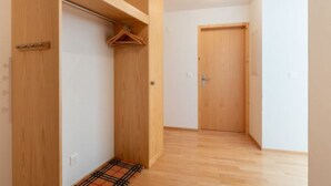 A hallway with wooden flooring, a coat rack, a door, and a small rug. - Capolgarten 3.7 by Interhome (Flims)